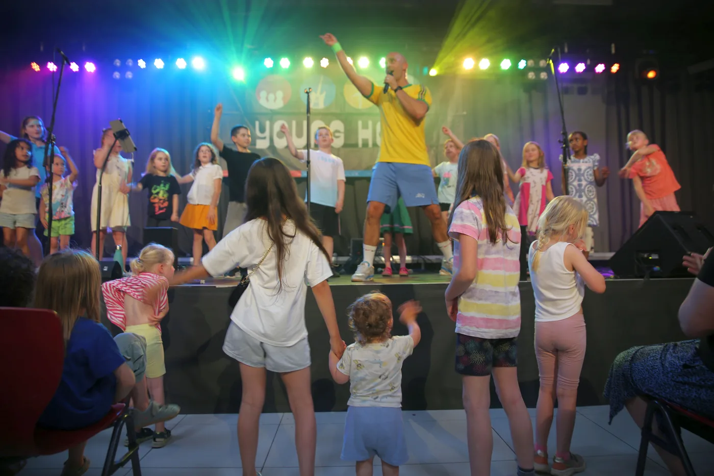 Kinder tanzen vor der Bühne, während Norbert Klotz beim Fitness-Pop Schultag auftritt